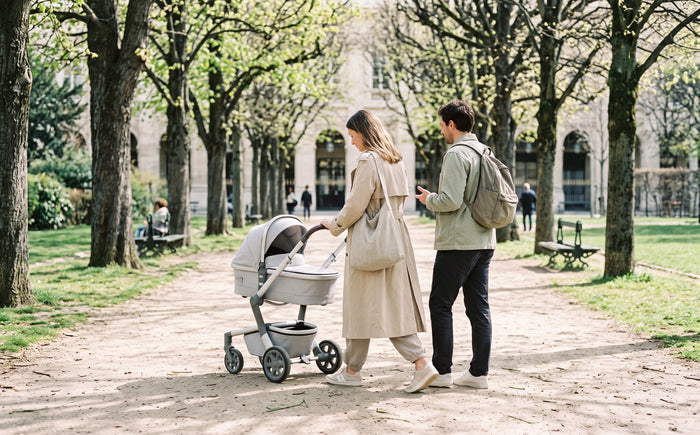 Famille en promenade avec une poussette dans une allée arborée